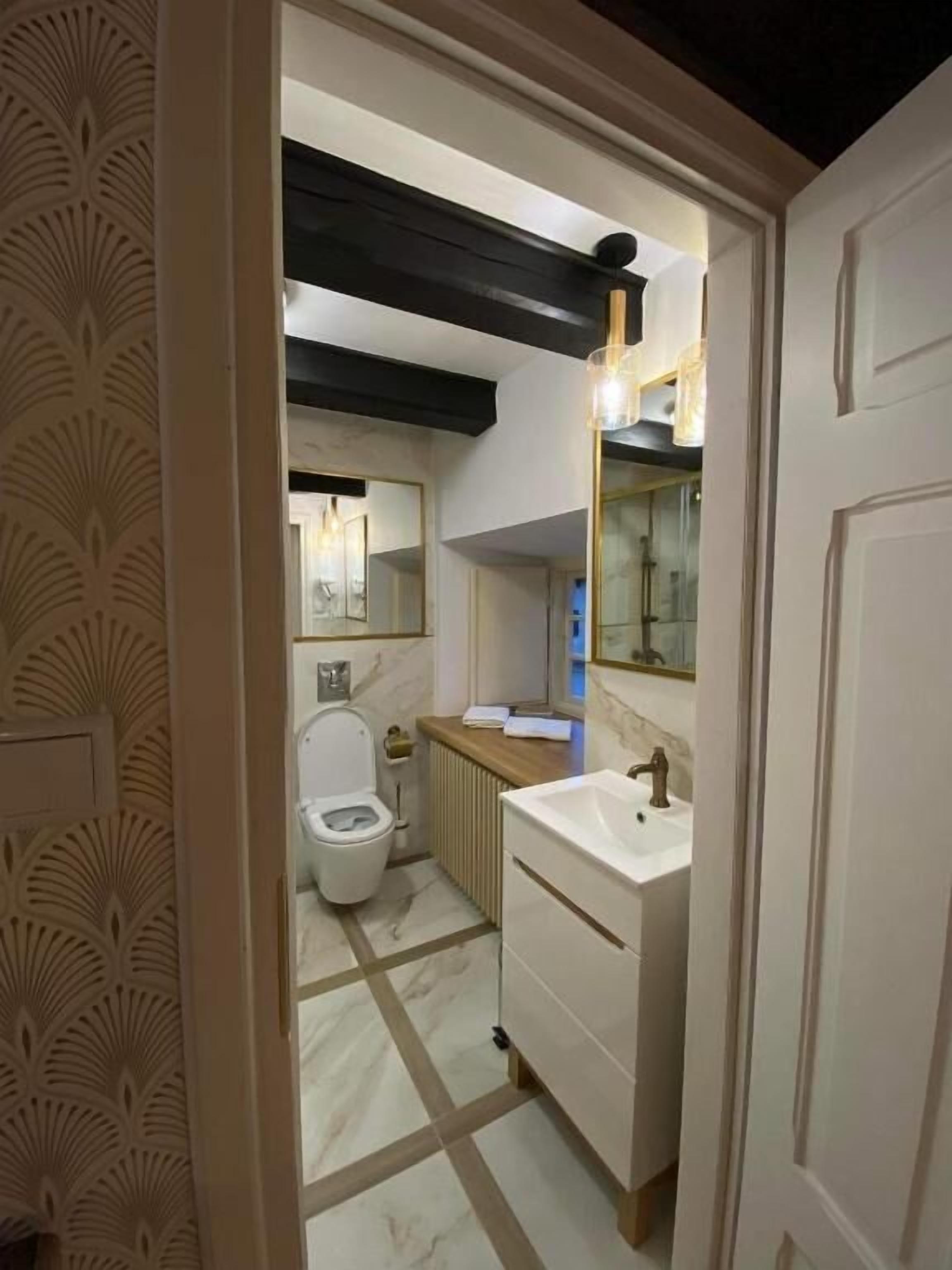 Un baño con inodoro, lavabo, espejo y radiador.