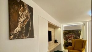 Un interior moderno con suelo de espiga, un sillón amarillo, un reposapiés verde y un cuadro abstracto de gran tamaño.