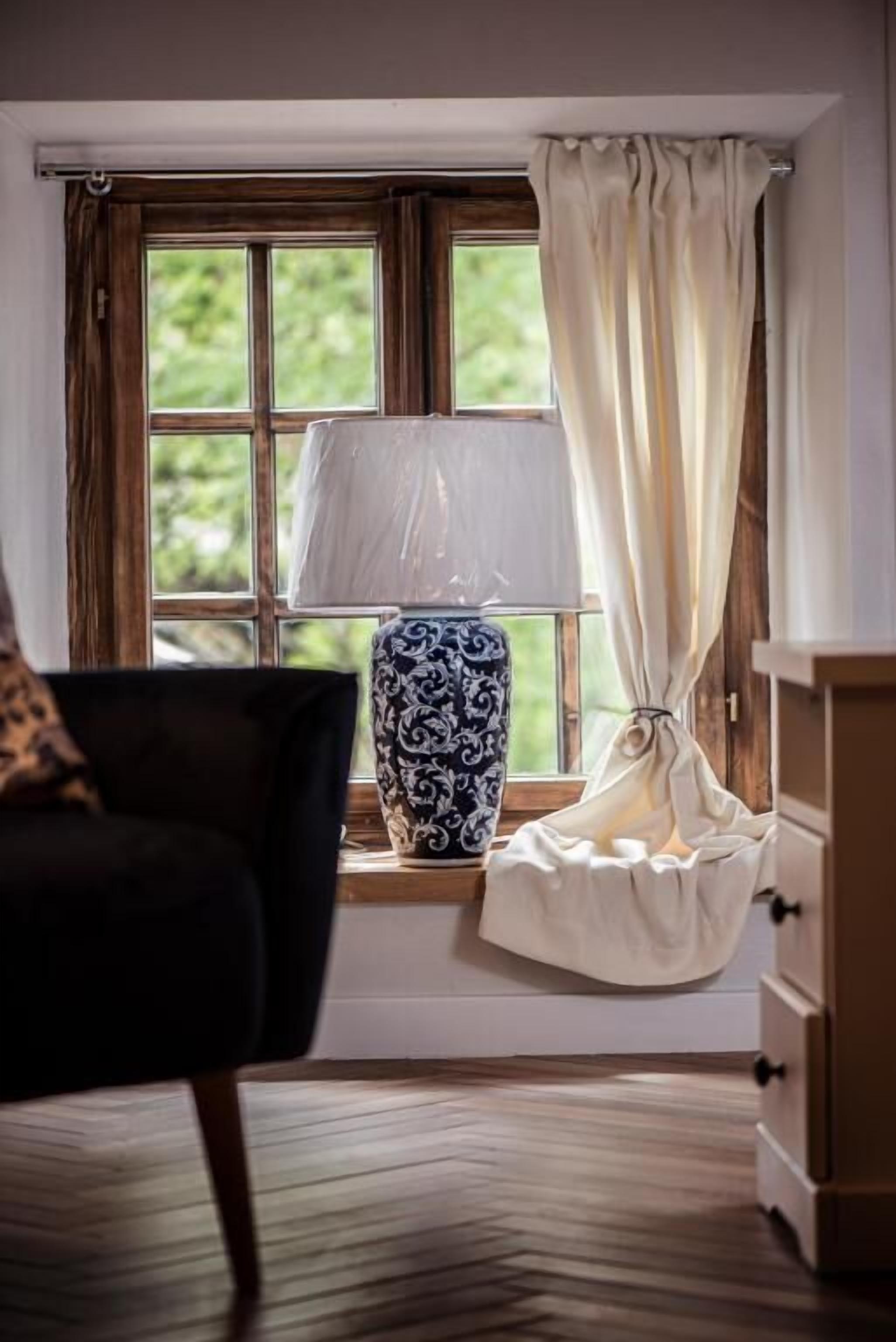 A room with a window, a lamp, a chair, and a dresser.