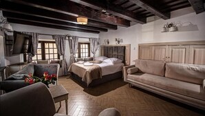 Una habitación con cama, sofá, una mesa con flores y televisor.