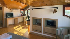 Una habitación acogedora con suelos de madera, televisor, chimenea y zona de comedor.