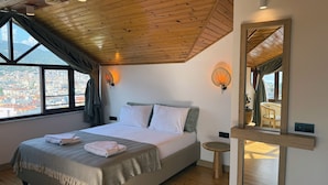 Un dormitorio con una cama grande, techo de madera y vistas a la ciudad a través de una ventana.
