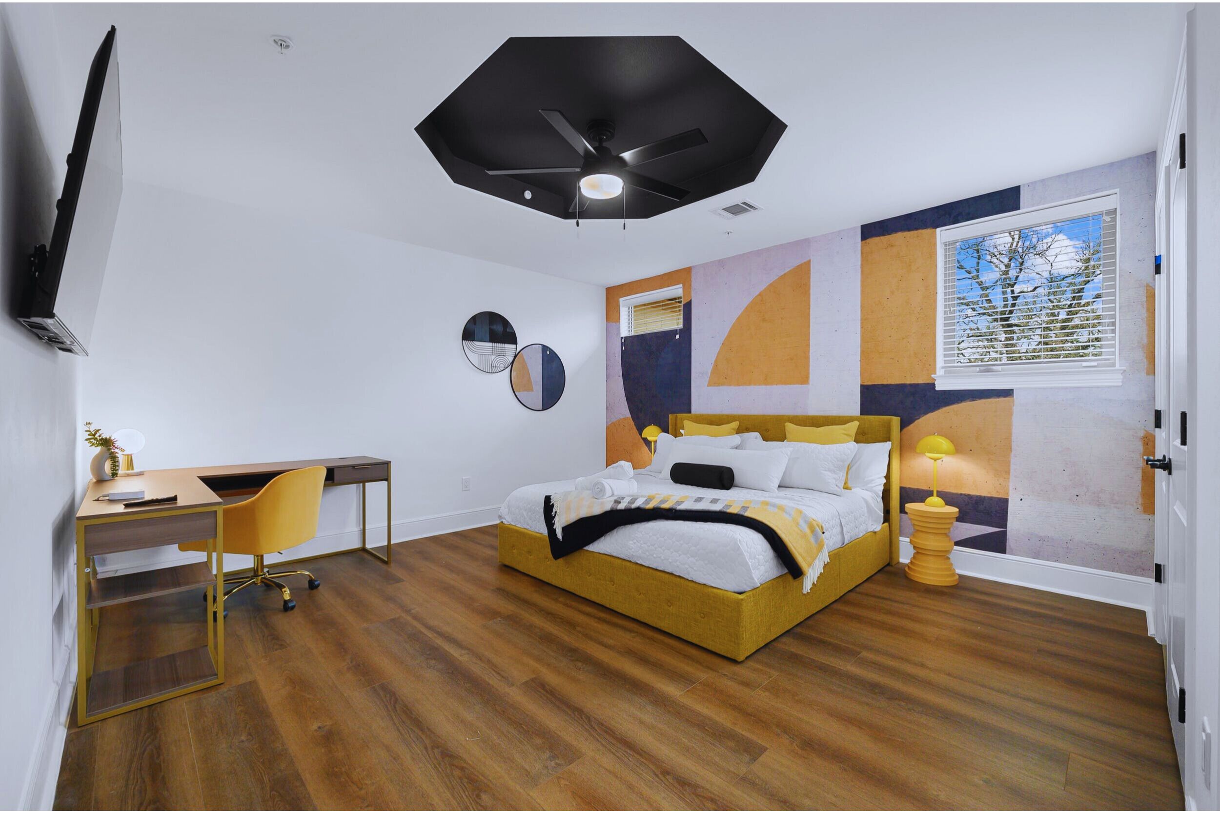 Ein Schlafzimmer mit Bett, Schreibtisch, Stuhl und Deckenventilator.