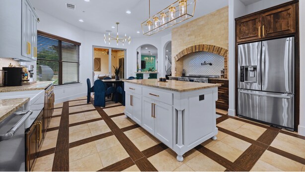 A modern kitchen with a central island, stainless steel appliances, and a brick fireplace. - 1110 Terjo Ln (Austin)
