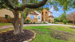A house with a stone facade, a large tree in the front yard, and a well-maintained lawn. - 1110 Terjo Ln (Austin)