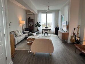 Ein stilvolles Wohnzimmer mit Sofa, Sessel, Esstisch und zwei Gitarren.