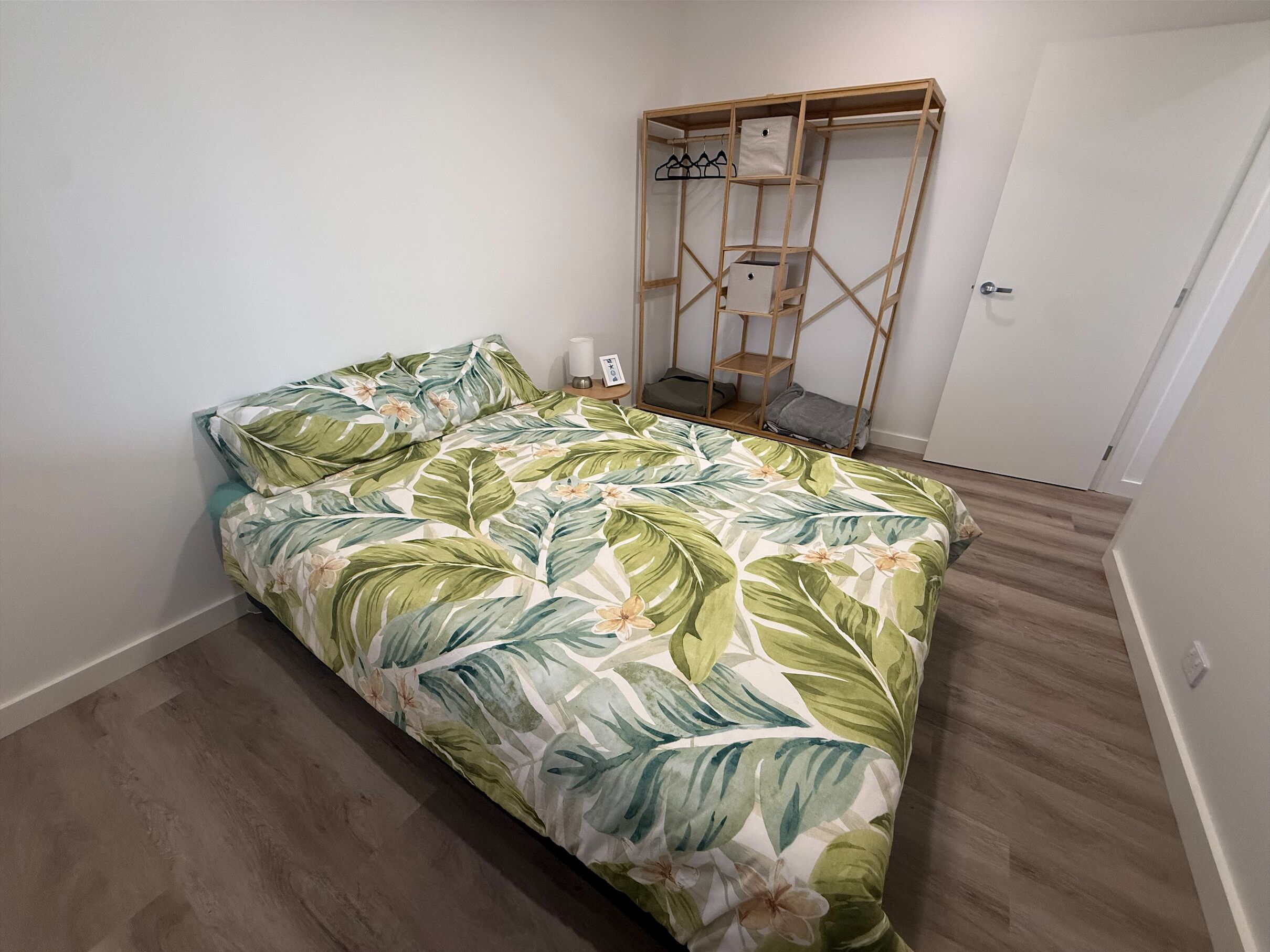 Une chambre à coucher avec un lit, une armoire en bois et une table de chevet avec une lampe.