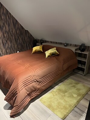A bedroom with a large bed, two pillows, a bedside table with a lamp, and a wooden headboard. - Holiday Home “Gîte Le Pré Salé” with Private Terrace and Wi-Fi (Boismont)