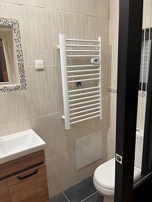A bathroom with a white sink, a toilet, a towel rack, and a mirror with a decorative frame. - Holiday Home “Gîte Le Pré Salé” with Private Terrace and Wi-Fi (Boismont)