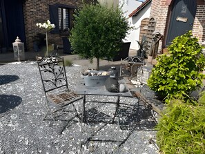 A courtyard with a metal table and chairs, a potted plant, and a small tree. - Holiday Home “Gîte Le Pré Salé” with Private Terrace and Wi-Fi (Boismont)