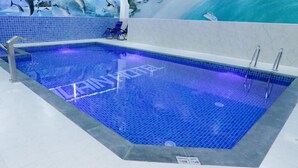 A swimming pool with a tiled edge, a depth sign, and a mural of dolphins.