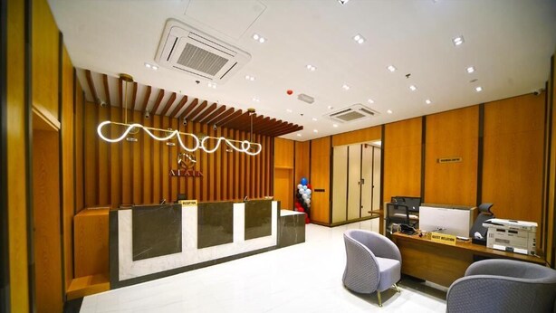 A reception area with a modern design, featuring a reception desk, seating area, and a sign for guest relations.