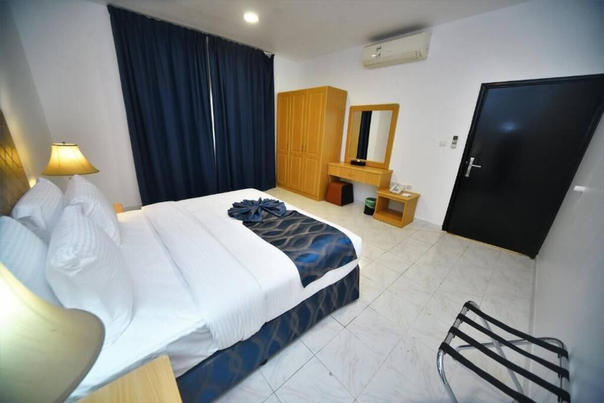 Habitació d'hotel amb llit, armari, mirall, escriptori i cadira.