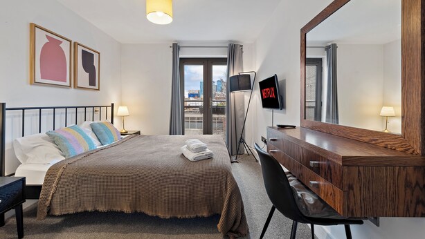 Une chambre d’hôtel comprenant un lit, une table de chevet, un bureau, une chaise et un grand miroir.