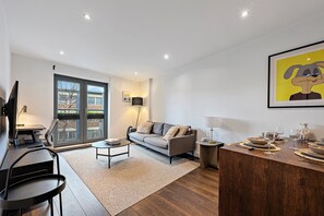 Ein modernes Wohnzimmer mit Sofa, Couchtisch und Essbereich mit Stühlen und Tisch für zwei Personen.