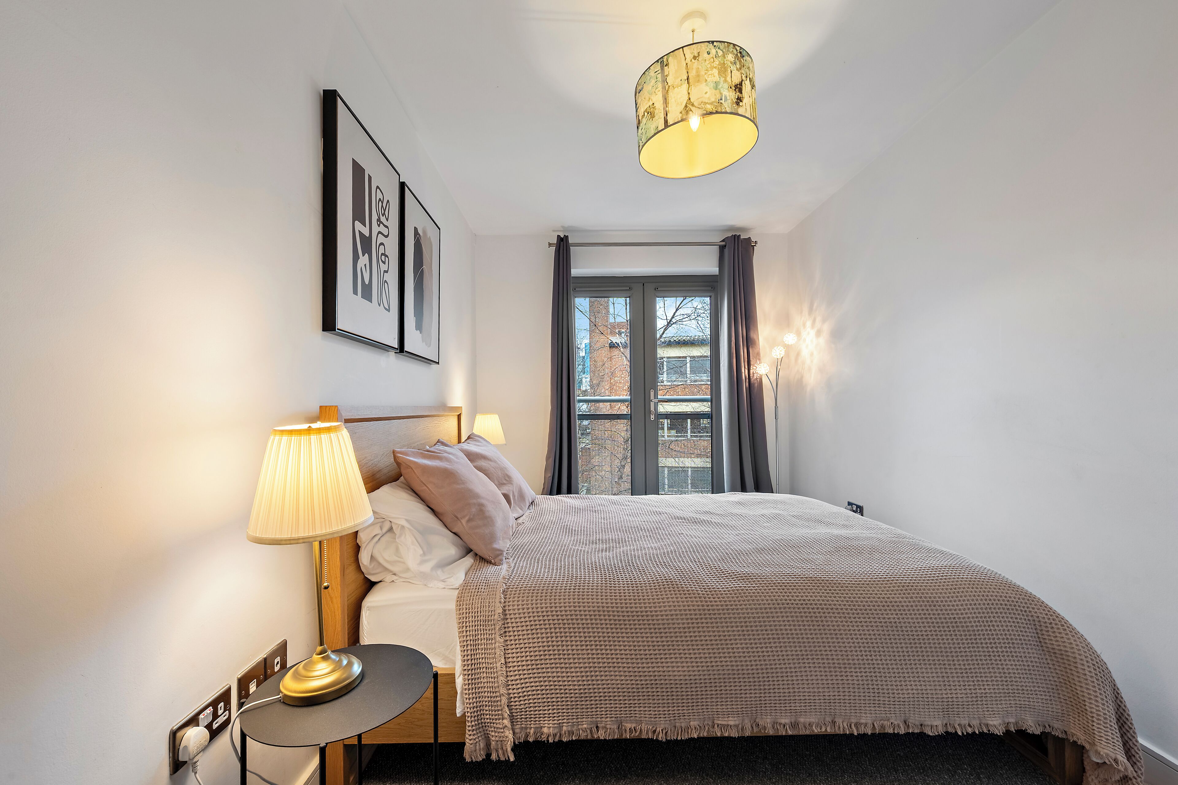 A bedroom with a bed, bedside lamp, and a window with curtains.