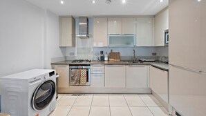 Une cuisine moderne dotée d’un lave-linge intégré, d’appareils électroménagers en acier inoxydable et d’un grand îlot central.