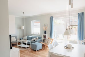 A modern living room with a sofa, coffee table, and dining area.