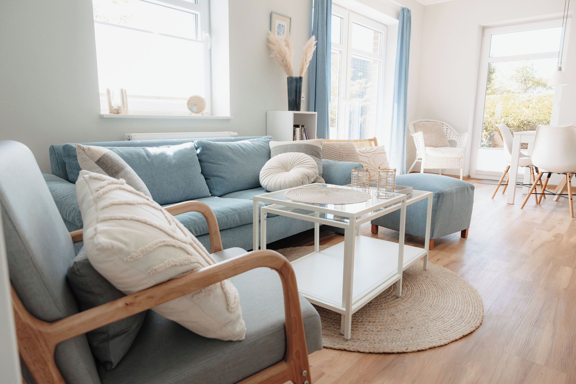 Una sala de estar moderna con un sofá, un sillón, una mesa de centro y un comedor con sillas.