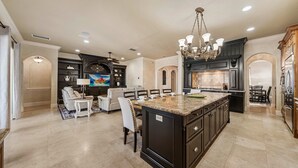 A spacious kitchen with a large island, dark cabinetry, and a chandelier. - 7811 Palmilla Court (Kissimmee)