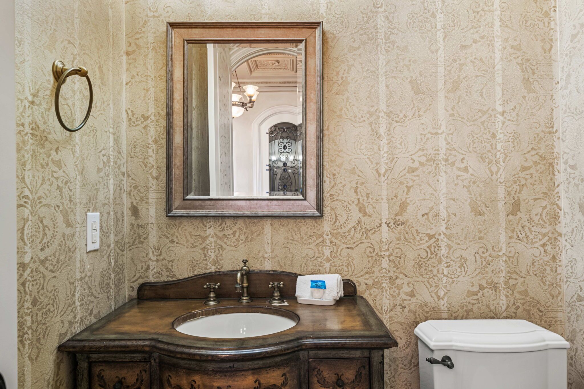 Ein Badezimmer mit einem Holzausleger, einem Spiegel, einer Toilette und Wandpapier mit Muster.