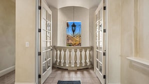 A hallway with a glass door leading to a balcony with a stained glass window. - 7811 Palmilla Court (Kissimmee)