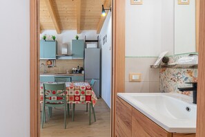 A compact kitchen with a dining area, wooden ceiling, and a white sink. - Casa 'Baglio Netino - Jasmine' Sea View with Kitchen, Wi-Fi, and Air Conditioning (Noto)