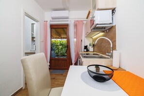 A compact kitchen with a sink, a microwave, and a window with curtains. - Modern vacation apartment in Crikvenica - close to the beach and comfortable (Crikvenica)