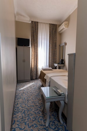 Une chambre d’hôtel équipée d’un lit, d’un bureau, d’une télévision, d’une armoire, d’un miroir et d’un appareil de climatisation.