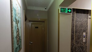 Un couloir avec une porte, un ascenseur et un panneau indiquant la sortie.