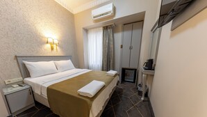 A hotel room with a bed, bedside lamp, air conditioning unit, and a small kitchenette. - Hotel Umit 2 (İstanbul)