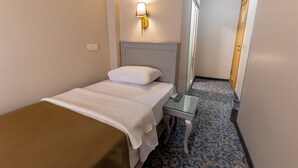 Une chambre d’hôtel avec un lit, une table de chevet, une lampe, un miroir et un sol recouvert de moquette.
