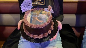 A person holding a birthday cake with a 'Happy Birthday' topper in a restaurant with booths and tables. - Fantastic building with AC in lovely Ashland (Ashland)