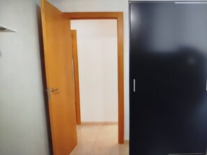 Un couloir avec une porte en bois sur la gauche et une armoire noire sur la droite.