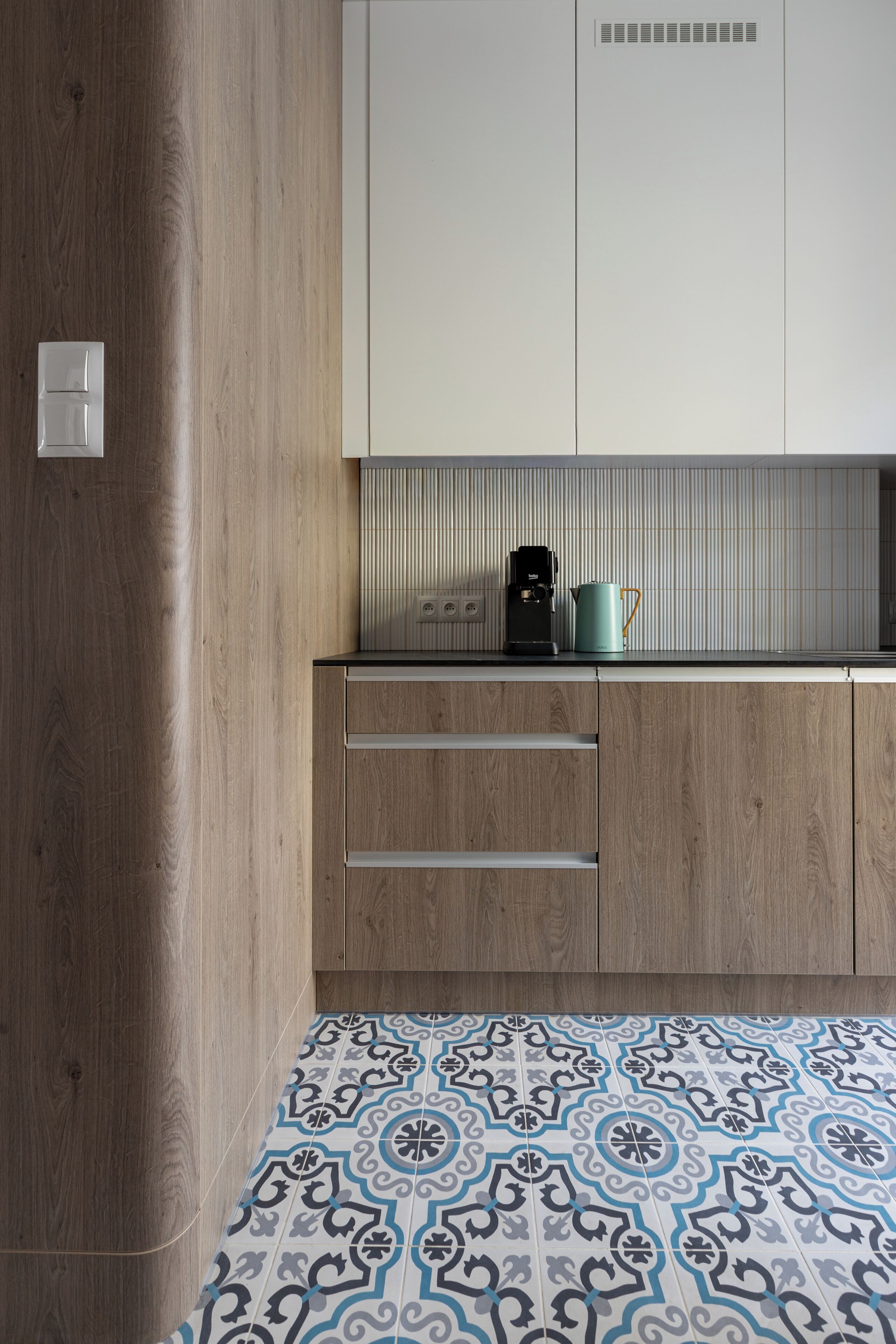 Una cocina con armarios de madera, salpicadero de azulejos y una cafetera en la encimera.