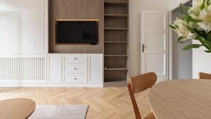 A modern interior with a wooden dining table, white cabinetry, and a mounted television. - Native Apartments Karłowicza 13 (Kraków)