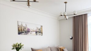 A modern living room with a sofa, a dining table with chairs, a coffee table, and a painting on the wall. - Native Apartments Karłowicza 13 (Kraków)
