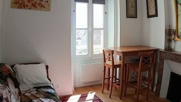 Una habitación con una mesa de madera, dos sillas, un sofá, una ventana con persianas y una chimenea.