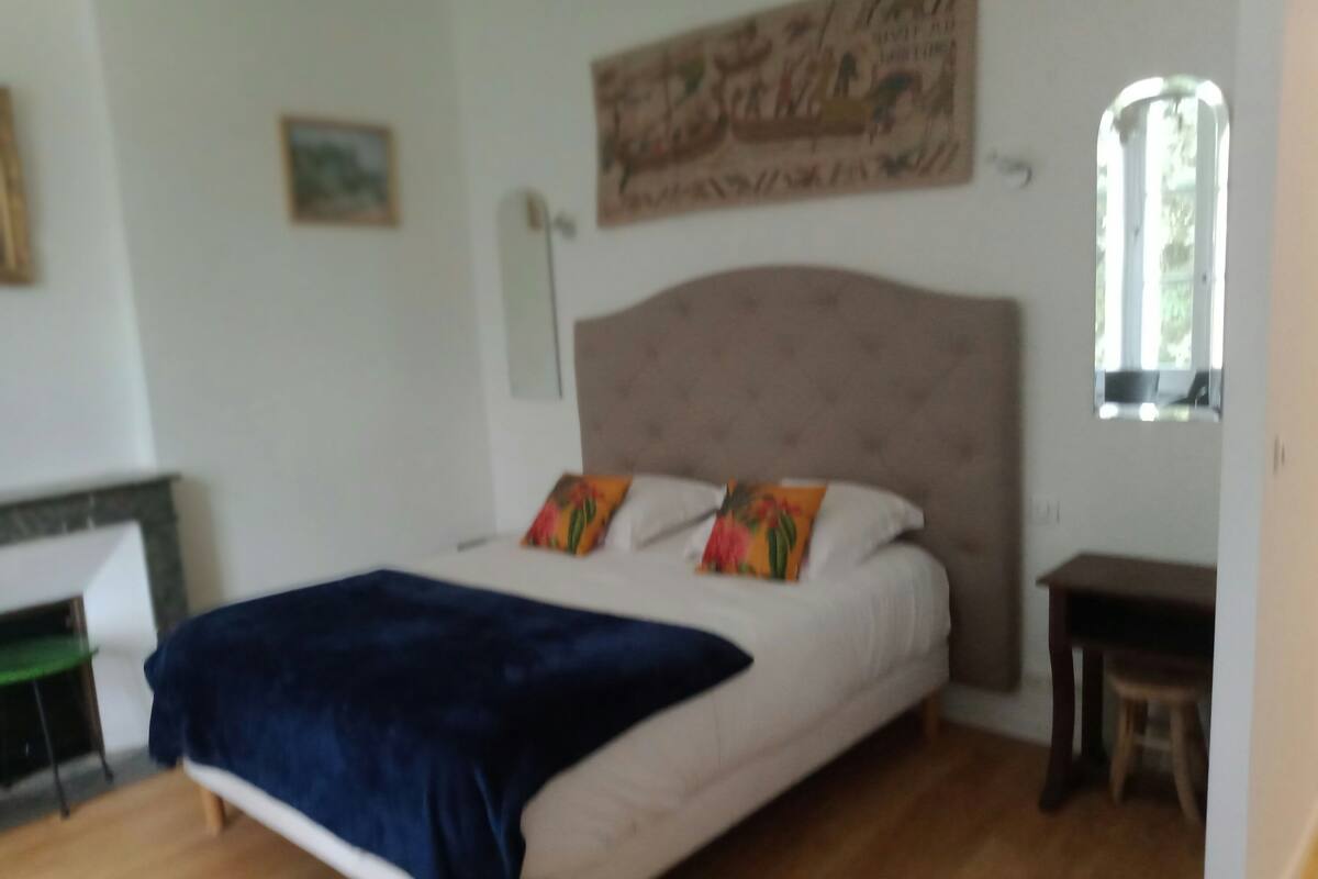 A bedroom with a bed, a window, and a painting on the wall.