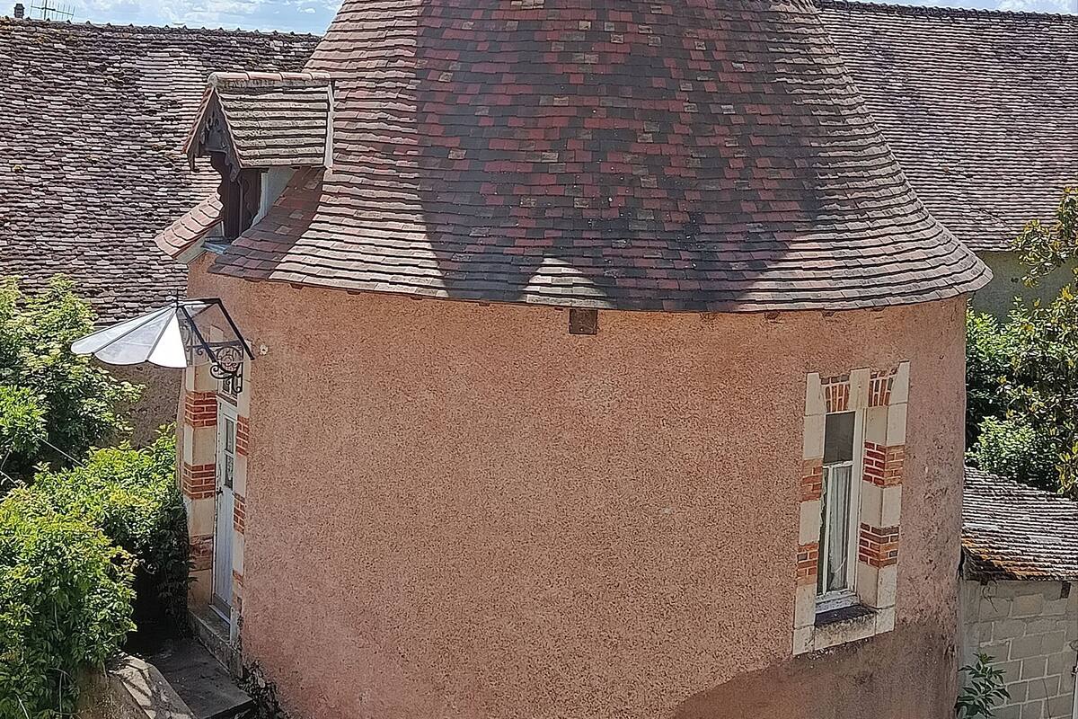 A building with a conical roof, a small window, and a brick facade.