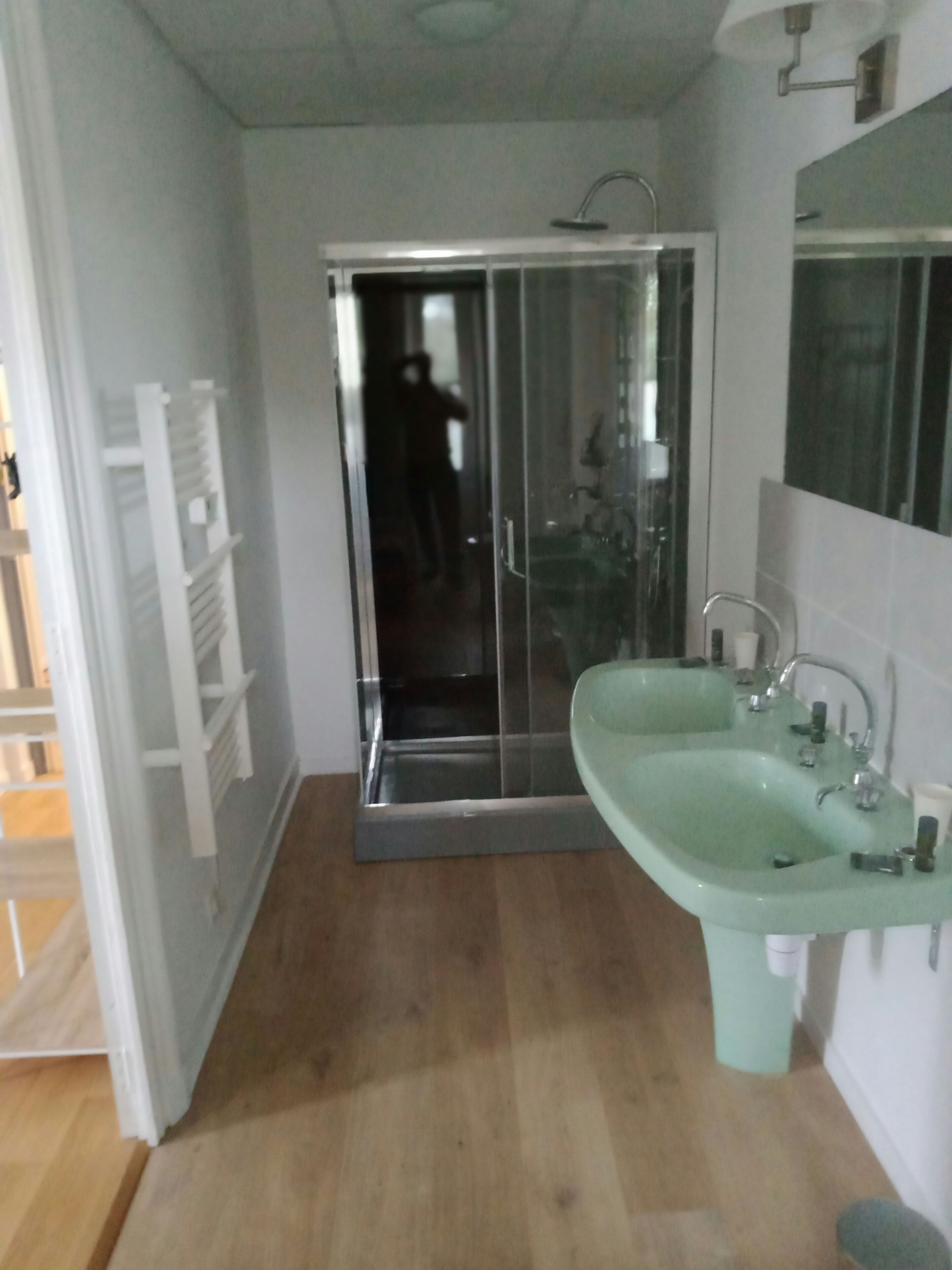 A bathroom with a glass shower enclosure, a sink, and a mirror.