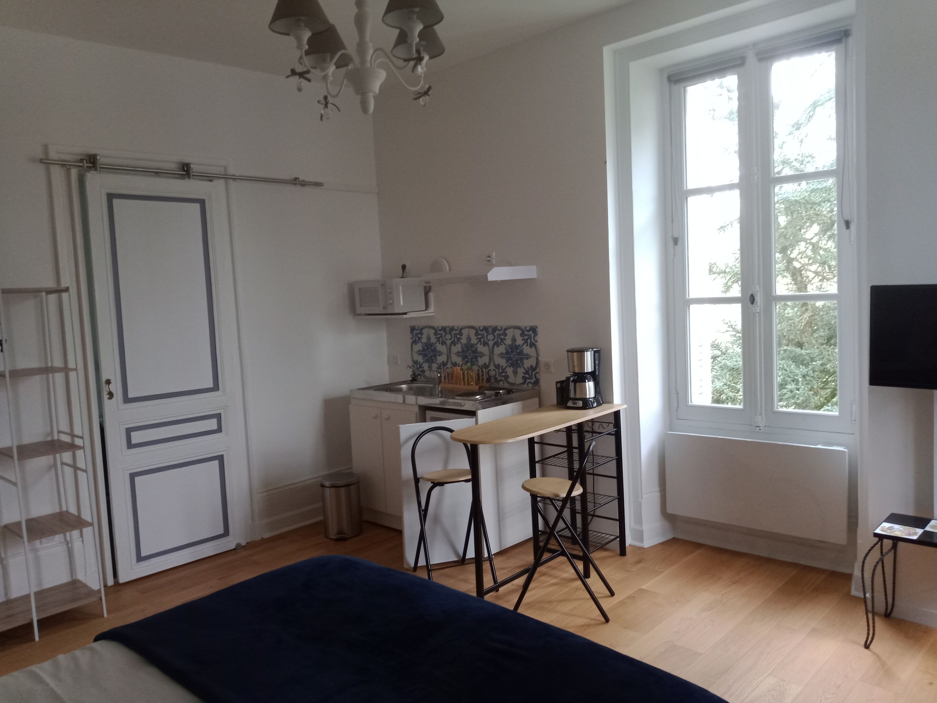 Una habitación con cama, un escritorio con silla, una ventana y un televisor.