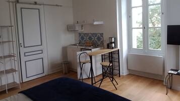 Una habitación con cama, un escritorio con silla, una ventana y un televisor.