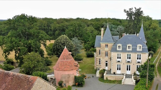 A large estate with a prominent tower and a main building with multiple windows and a steep roof. - VILLA SAINT-PIERRE (La Trimouille)