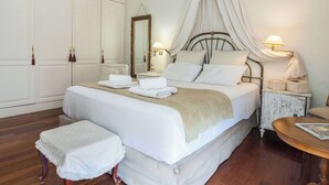 Un dormitorio con una cama grande, mesitas de noche, un armario y una pequeña mesa redonda.