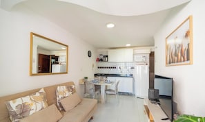 A compact living space with a sofa, dining table, kitchen area, and a large mirror. - Apt in Condo w/ Pool 110m From the Beach Vem0306 (João Pessoa)