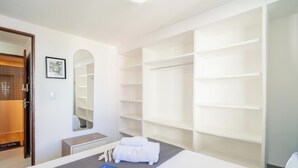 A hotel room with a large wardrobe, a mirror, and a bed with a white towel. - Apt in Condo w/ Pool 110m From the Beach Vem0306 (João Pessoa)