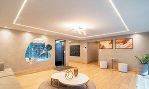 A modern hotel lobby with a round table, a reception desk, and a large mirror. - Apt in Condo w/ Pool 110m From the Beach Vem0306 (João Pessoa)