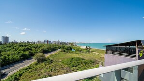 A modern building with a balcony overlooking a coastal area, a road, and a cityscape in the background. - Apt in Condo w/ Pool 110m From the Beach Vem0306 (João Pessoa)