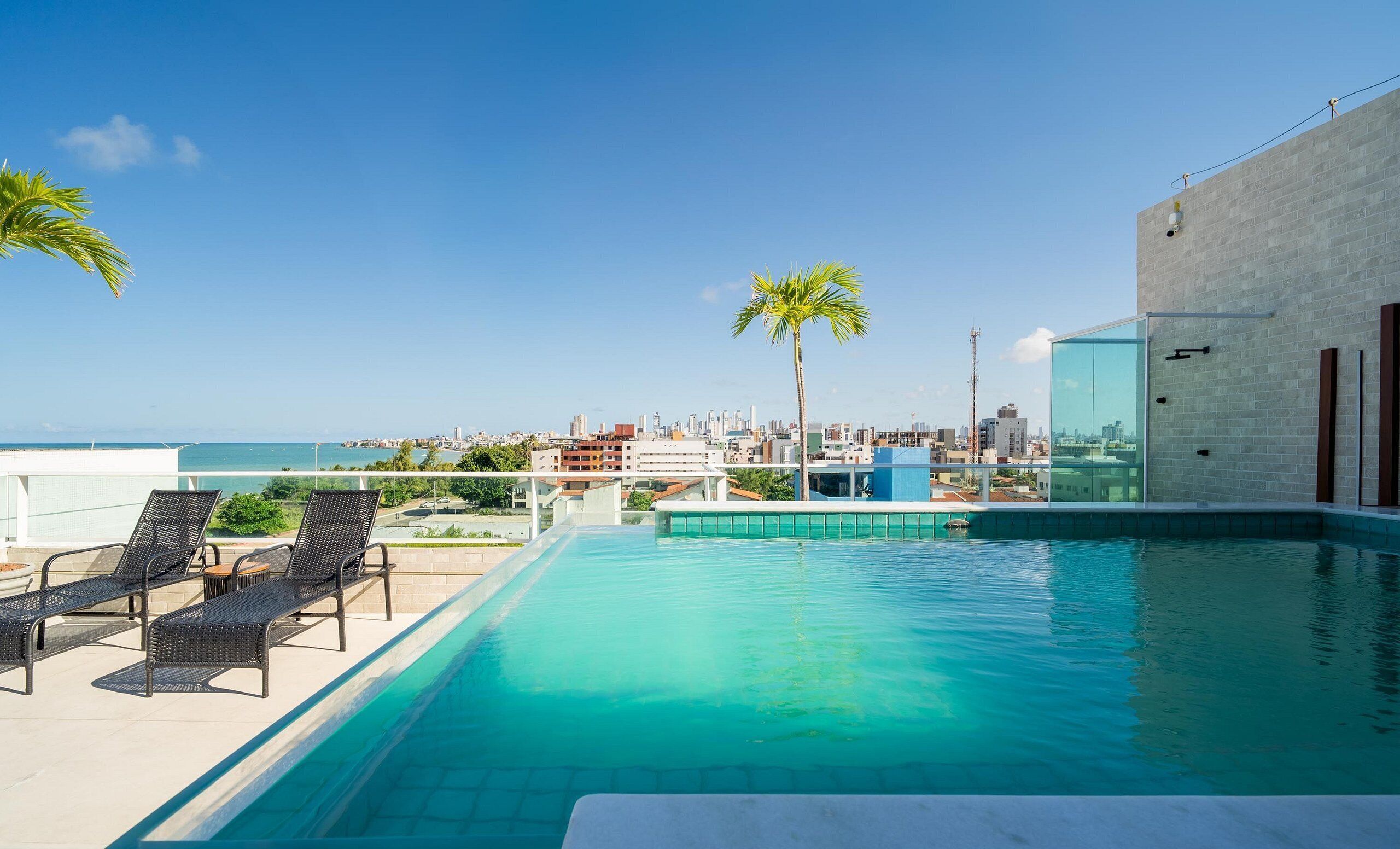A rooftop pool with lounge chairs and a city view.